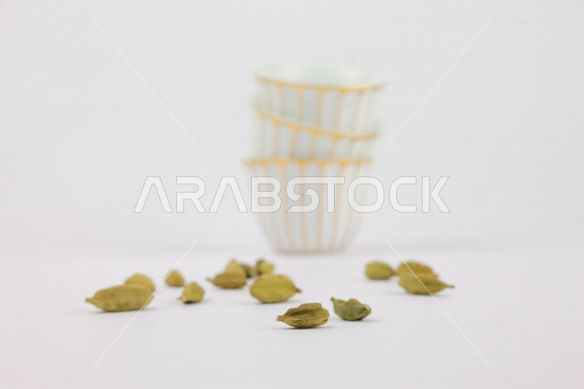 صورة لمجموعة من فناجين القهوة وحبوب الهيل المتناثرة ، القهوة العربية الخليجية ، ضيافة رمضانية ، اعياد ومناسبات 