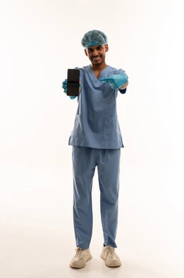 ممرض سعودي يشير إلى هاتف ذكي بالزي الطبي