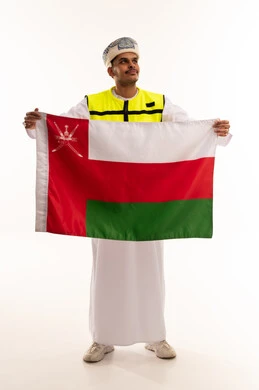 رجل عماني يحمل العلم ويرتدي سترة السلامة