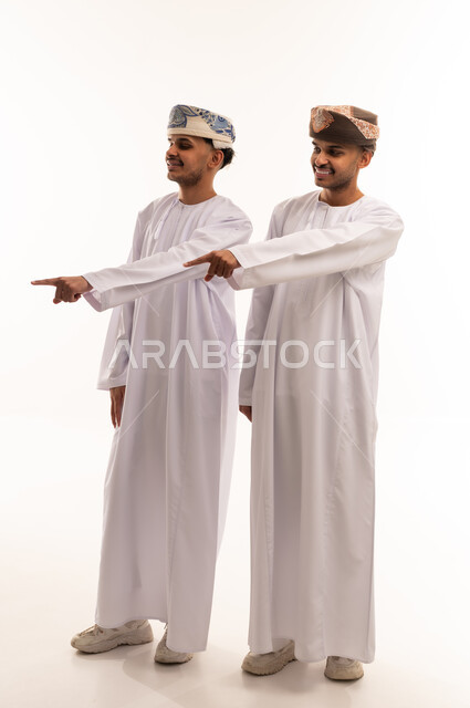 رجال عمانيون بالزي التقليدي يشيرون نحو الجانب