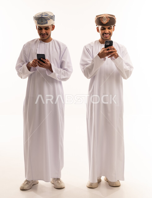 رجال عمانيون بالزي التقليدي يستخدمون الهواتف الذكية