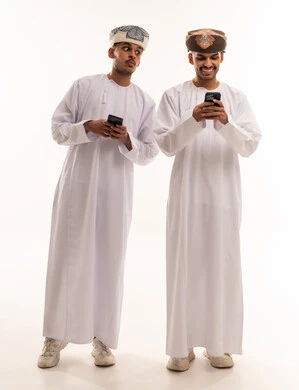 رجلان عمانيان يستخدمان الهواتف الذكية بخلفية بيضاء