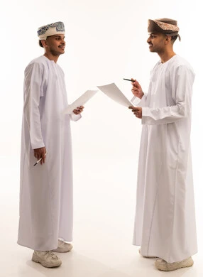 Omani Men in Traditional Dress Reviewing Documents