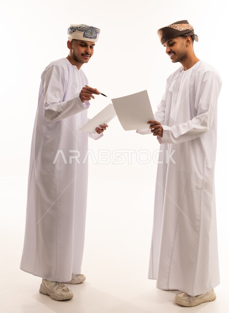 Omani Men in Traditional Dress Reviewing Documents
