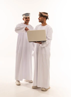 رجال عمانيون بالزي التقليدي يستخدمون حاسوب محمول