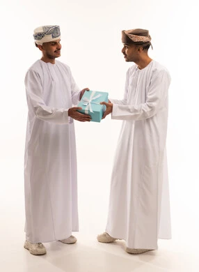 Omani Men in Traditional Dress Exchanging a Gift Box
