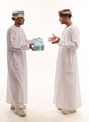 Omani Men in Traditional Dress Giving Gift Box Studio