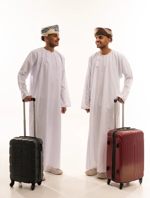 رجال عمانيون بزي تقليدي مع حقائب سفر في استوديو