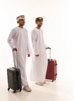 رجال عمانيون بزي تقليدي مع حقائب سفر