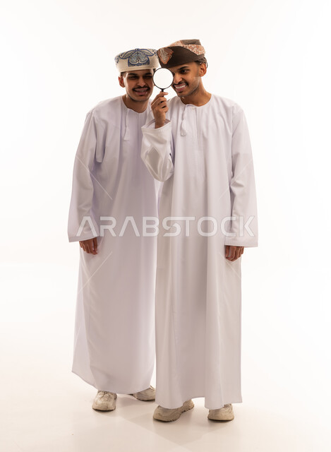 Omani Men in Traditional Dress Using Magnifying Glass