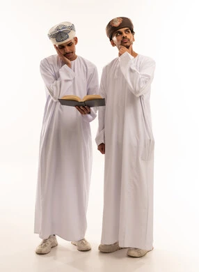 رجال عمانيون بالزي التقليدي يقرؤون ويفكرون