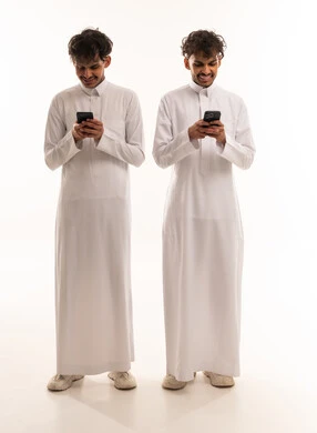 شبان سعوديون بالثوب التقليدي يستخدمون الهواتف الذكية