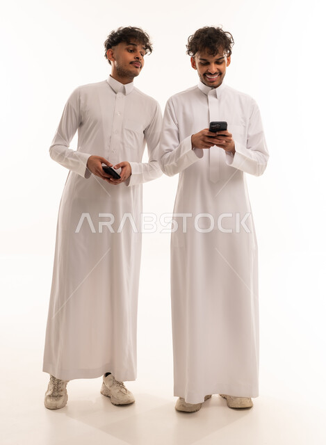 شباب سعوديون بالثوب التقليدي يستخدمون الهواتف الذكية