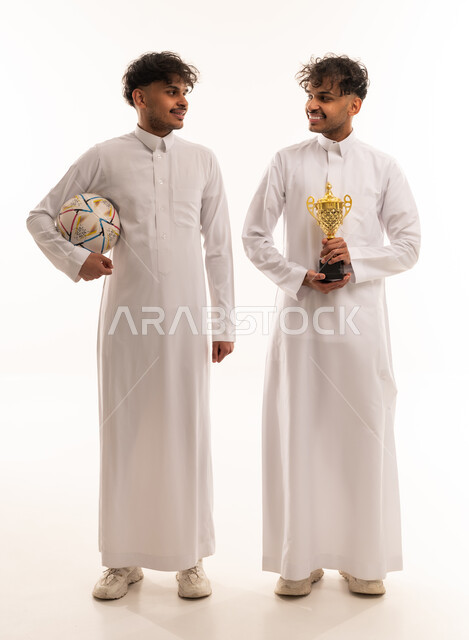 رجلان سعوديان مع كرة قدم وكأس ذهبية