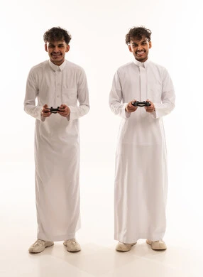 شابان عربيان بالثوب التقليدي يحملان وحدات تحكم الألعاب