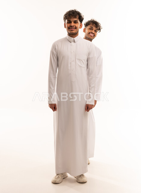 شابان سعوديان بالثوب التقليدي أمام خلفية بيضاء