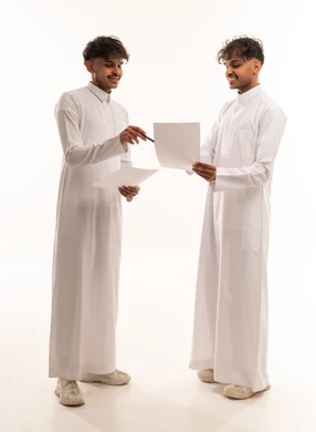 Saudi Men in Traditional Thobes Discussing Documents