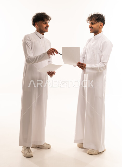 Saudi Men in Traditional Thobes Discussing Documents