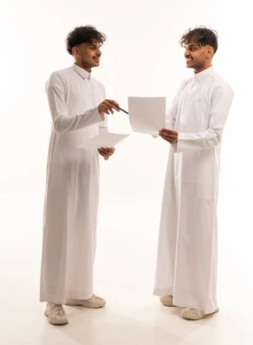 Saudi Men in Traditional Thobes Discussing Documents