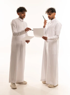 Two Saudi Men in Traditional Thobes Discussing Papers