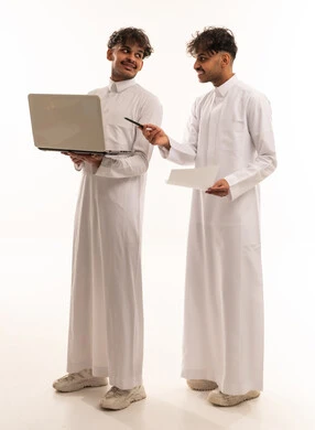 Two Saudi Men in White Thobes Using Laptop