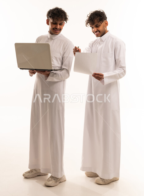 رجال سعوديون يستخدمون الكمبيوتر المحمول والورقة بخلفية بيضاء