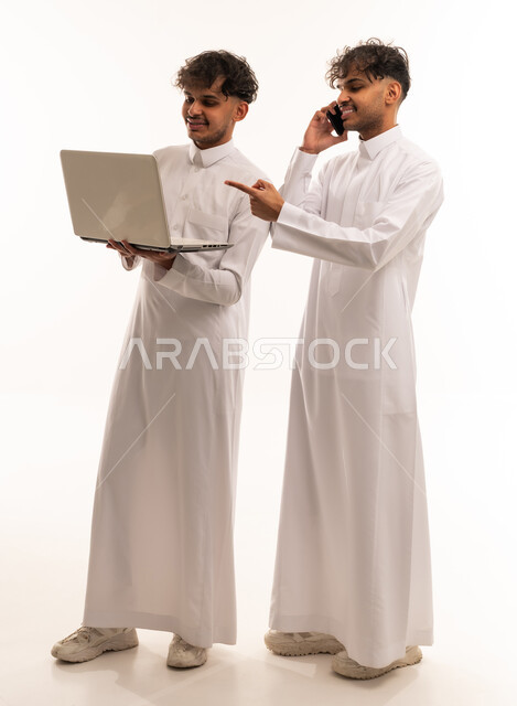 رجال سعوديون بالثوب يستخدمون الكمبيوتر والهاتف