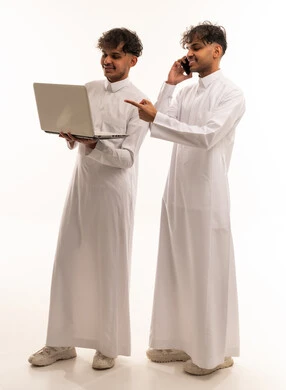رجال سعوديون بالثوب يستخدمون الكمبيوتر والهاتف