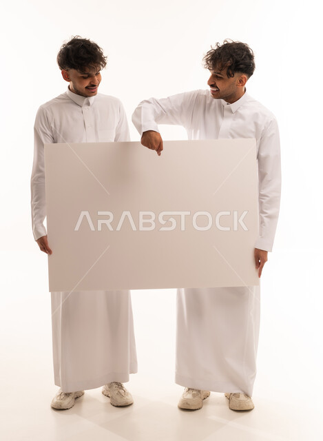 شباب سعوديين يمسكون بلوحة إعلانية بيضاء فارغة