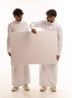 شباب سعوديين يمسكون بلوحة إعلانية بيضاء فارغة