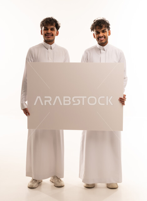 شباب سعوديون يحملون لوحة بيضاء فارغة في الاستوديو