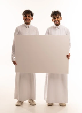 شباب سعوديون يحملون لوحة بيضاء فارغة في الاستوديو