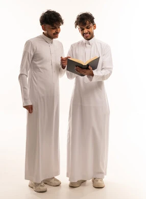 Two Saudi Men in Traditional Thobes Reading a Book
