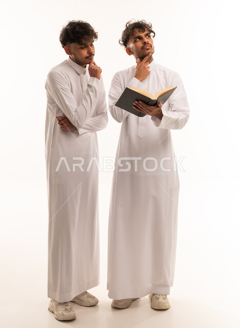 رجال سعوديون بالثوب الأبيض يفكرون مع كتاب