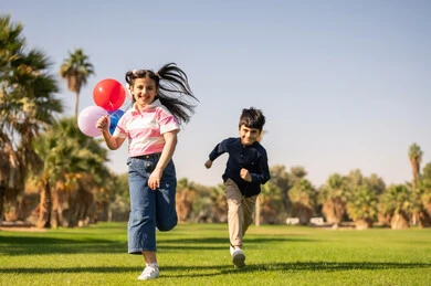 أطفال سعوديون يركضون في حديقة عامة مع بالونات