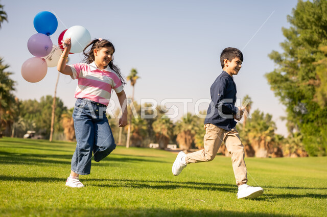 Arab Children Running with Balloons in Public Park