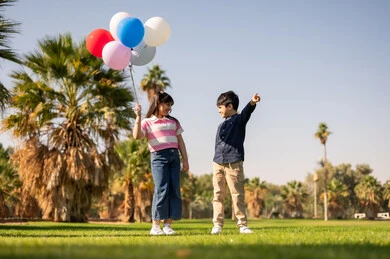 أطفال عرب يحملون بالونات في حديقة عامة