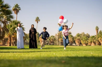 عائلة سعودية تلعب بالبالونات في حديقة عامة