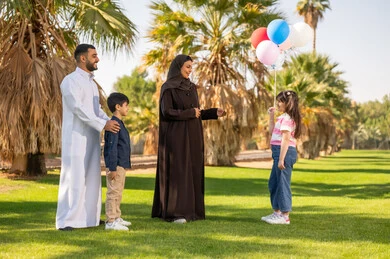 عائلة سعودية في الحديقة مع بالونات ملونة عائلة سعودية في الحديقة مع بالونات ملونة