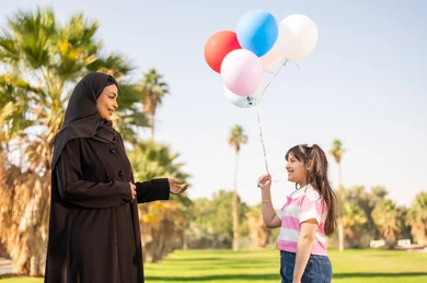 أم سعودية وابنتها مع بالونات في حديقة عامة