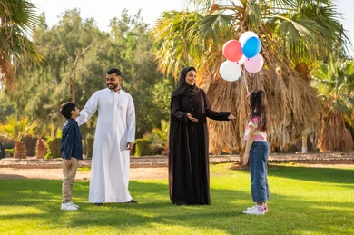 عائلة إماراتية في الحديقة مع بالونات وملابس تقليدية
