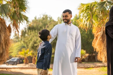 أب سعودي مع ابنه بالثوب التقليدي في الحديقة