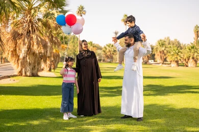 عائلة سعودية مع أطفال وبالونات في حديقة عامة