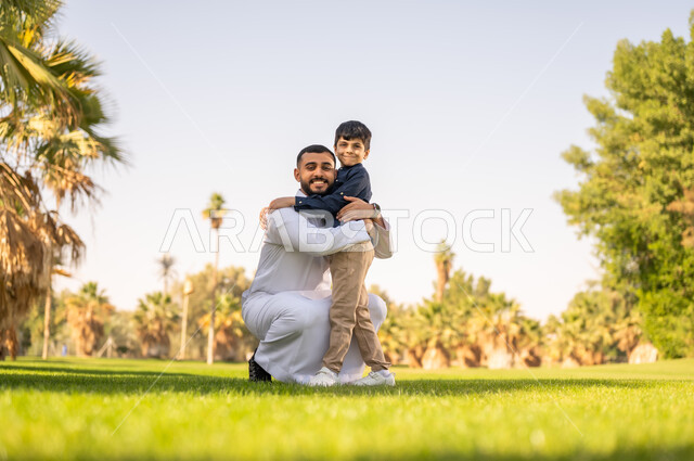 أب إماراتي يحتضن ابنه في حديقة مشمسة
