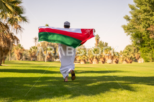 رجل عماني يركض مع العلم الوطني في الحديقة
