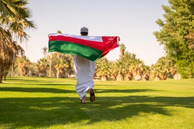Omani Man Running with National Flag in Park