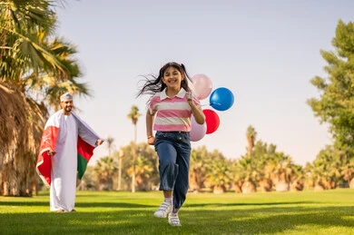طفلة عمانية ووالدها يحتفلان باليوم الوطني في الحديقة