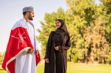 Omani Man and Woman in Traditional Dress with Flag in Park