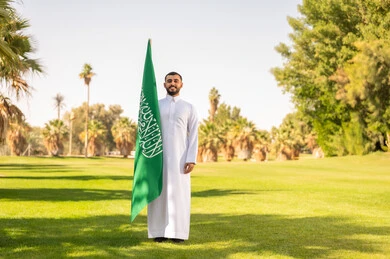 Saudi Man Holding Flag in Green Park Daytime