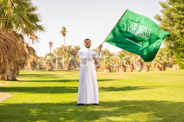 رجل سعودي يحمل العلم في حديقة خضراء